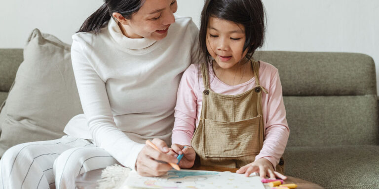 mom smiling at daughter while she colors some winter coloring pages