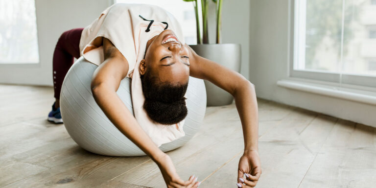 woman stretching over a pilates ball - pelvic floor exercises