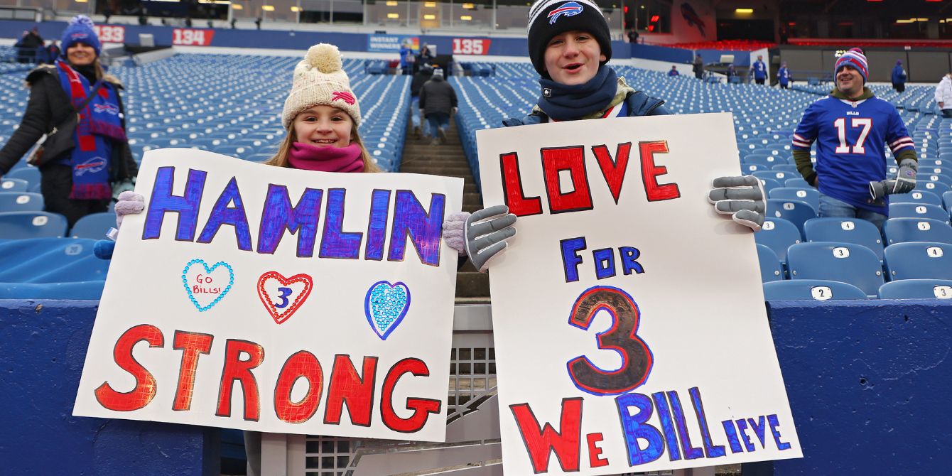 Two kid football fans hold signs to support Damar Hamlin - should I let my kid play football?