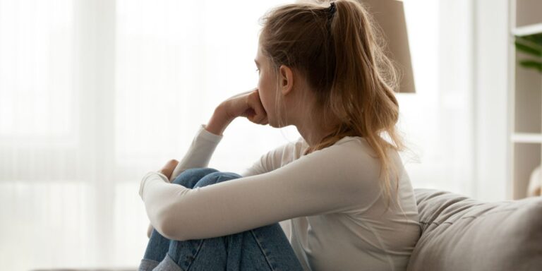 sad teen at home on couch looking away - birth control and depression