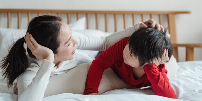 mom talking to son on bed - how to talk to kids about periods