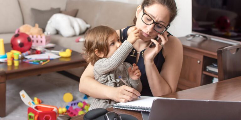 mom struggling to work with baby on lap- annual cost of childcare