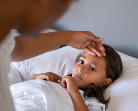 mom feels childs forehead for fever Motherly