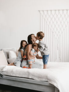 Mom hugging and cuddling young children at home - 2023 State of Motherhood