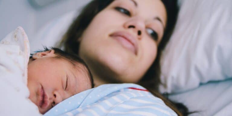 mother with her newborn baby in hospital bed - motherhood imposter syndrome