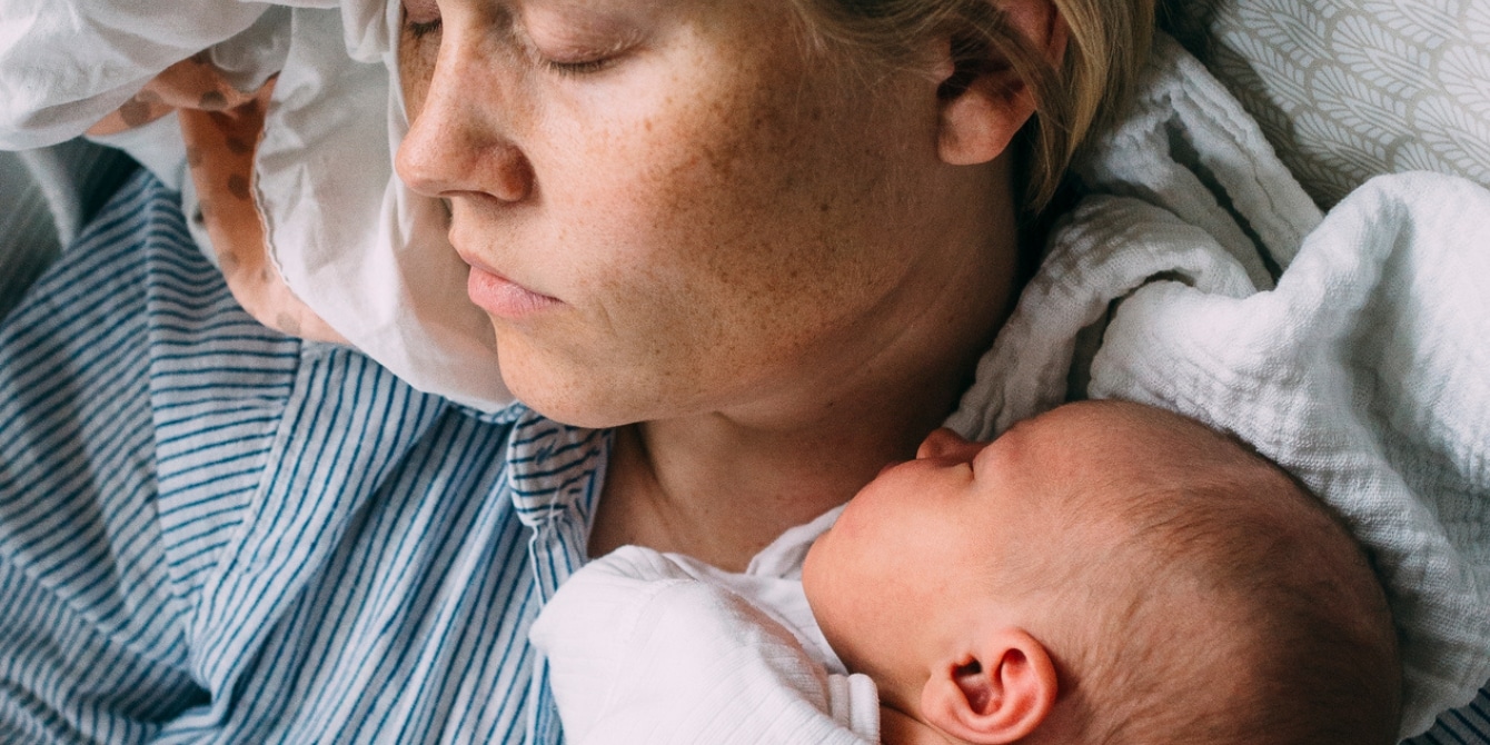 New Mother Does Yoga On A Mat While Nursing Child by Stocksy