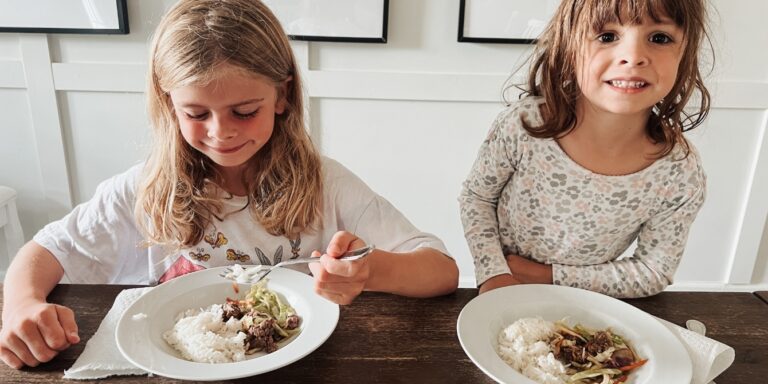 two-young-girls-eating-dinner-at-table