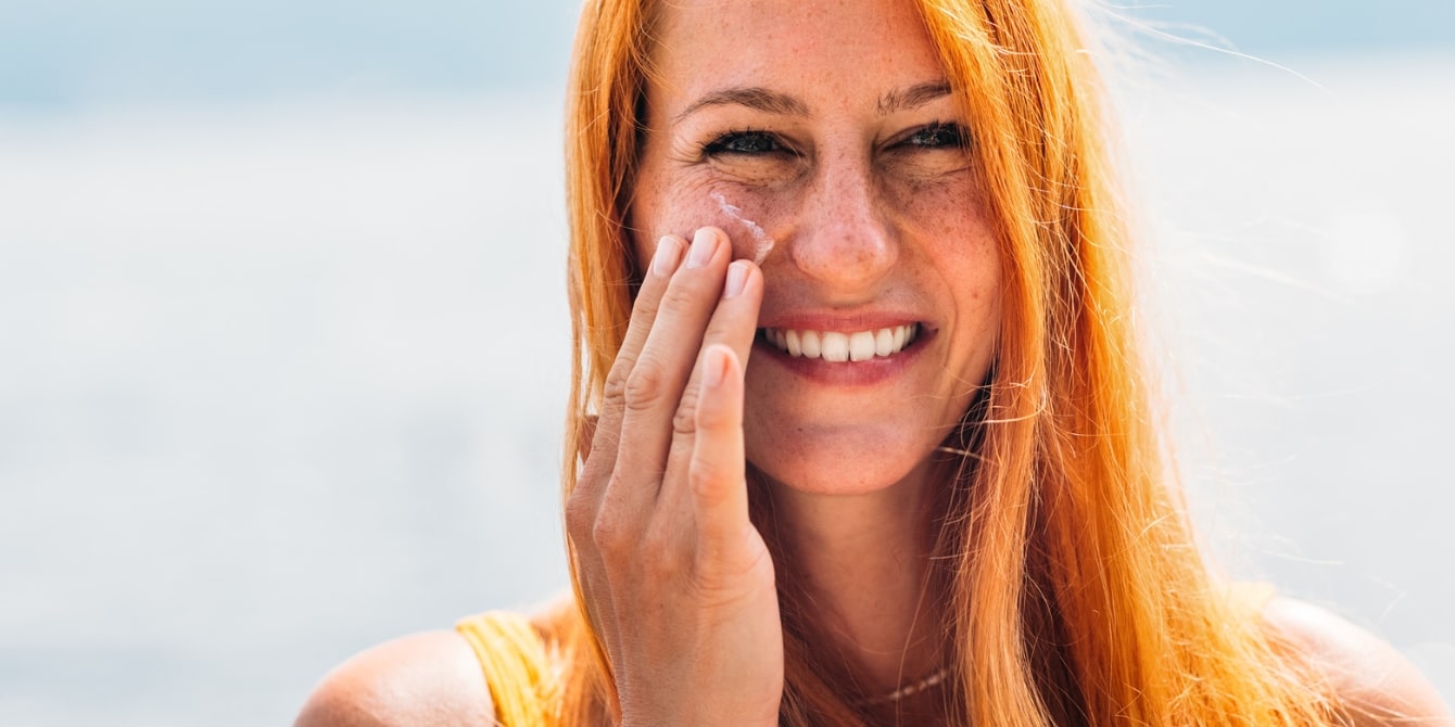 woman applying sunscreen to face - sunscreen rules