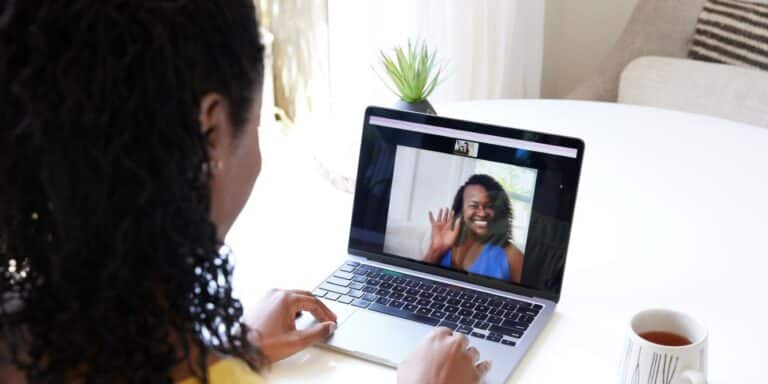 Mature black girlfriends doing a zoom call together on computer waving - group therapy for ppd