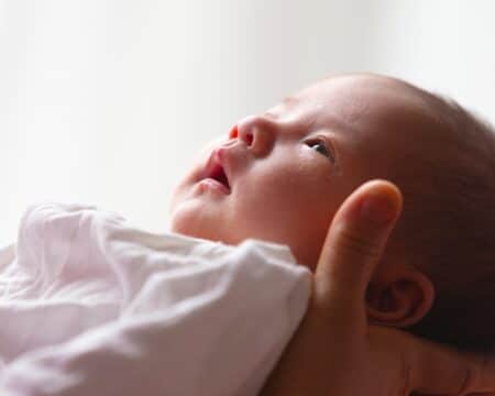 close up of parent holding newborn baby Motherly