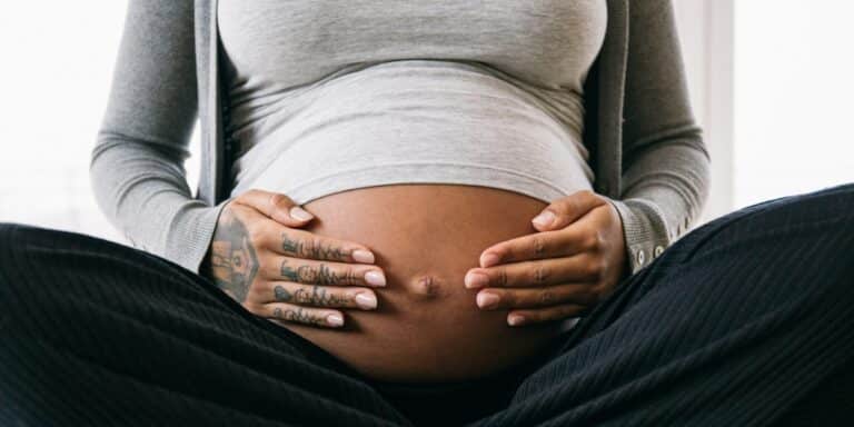 cropped pregnant woman sitting touching belly - microchimerism