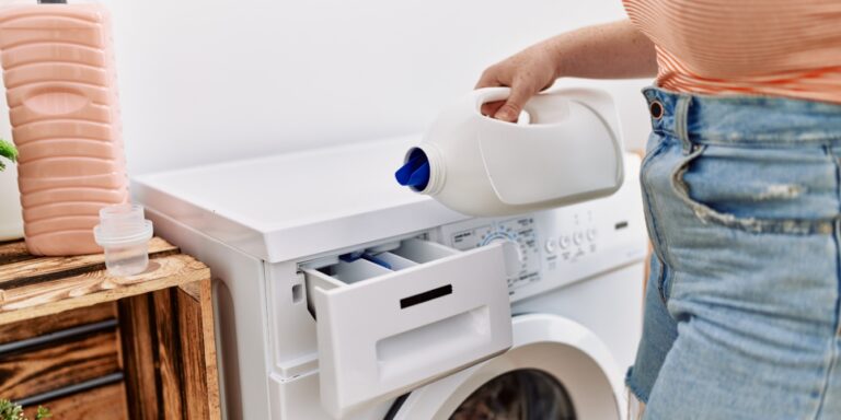 hand pouring liquid laundry detergent into washing machine