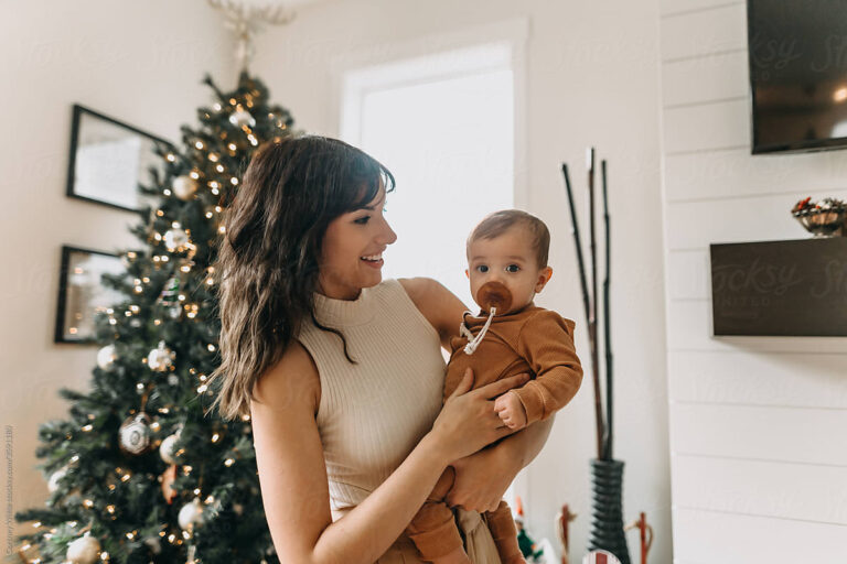 mom holding baby in front of christmas tree - best gifts for new moms