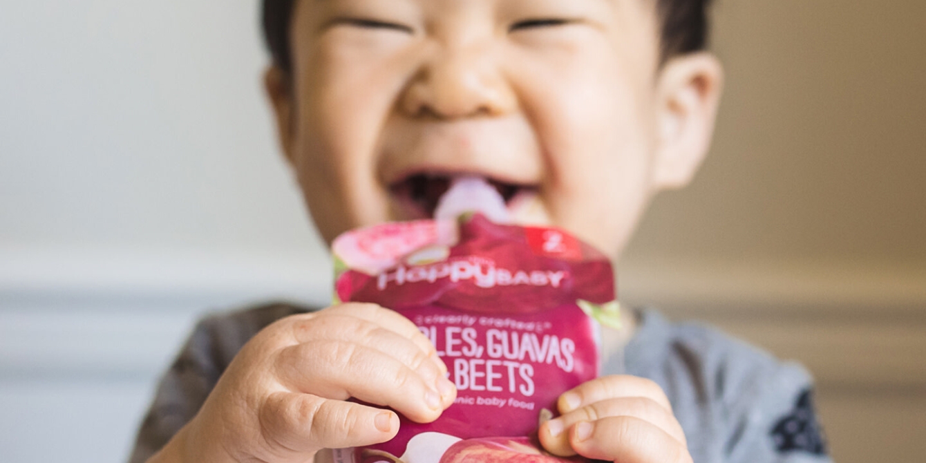 https://www.mother.ly/wp-content/uploads/2023/10/boy-in-highchair-laughing-while-eating-happy-baby-pouch.jpeg