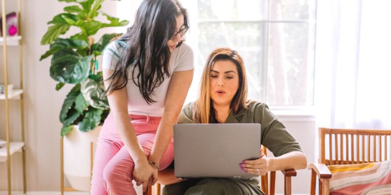 Mother filling out something on computer with teen