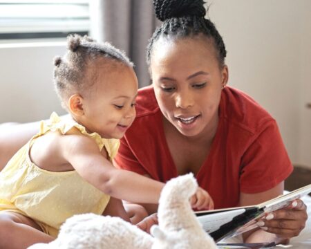 mom and toddler girl reading books together Motherly