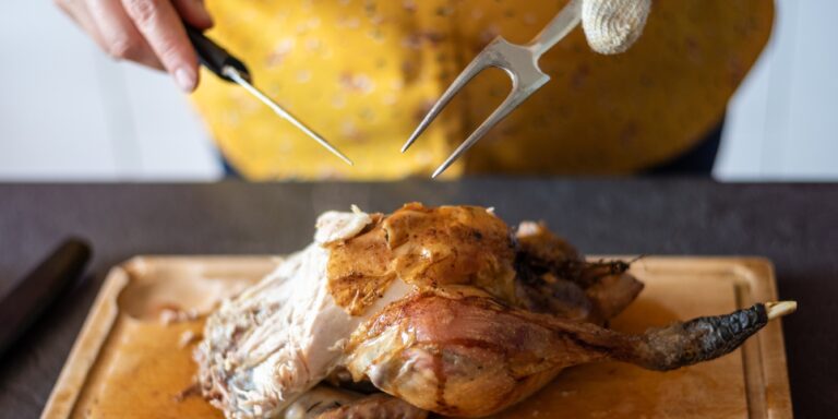 woman carving thanksgiving turkey - can i eat thanksgiving turkey while pregnant