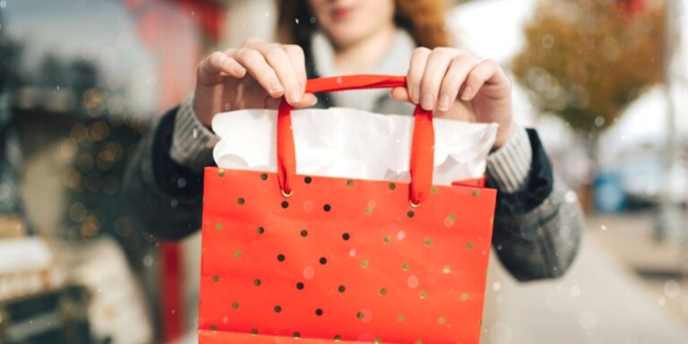 woman holding out christmas shopping bag holidays christmas financial stress