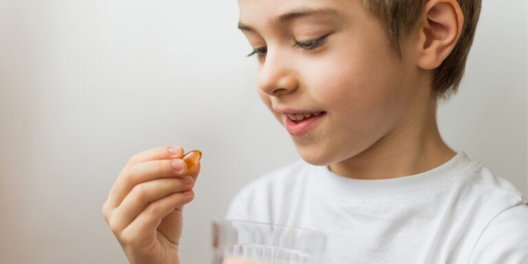 young boy holding pill get kids to swallow pills how to help kids swallow pills