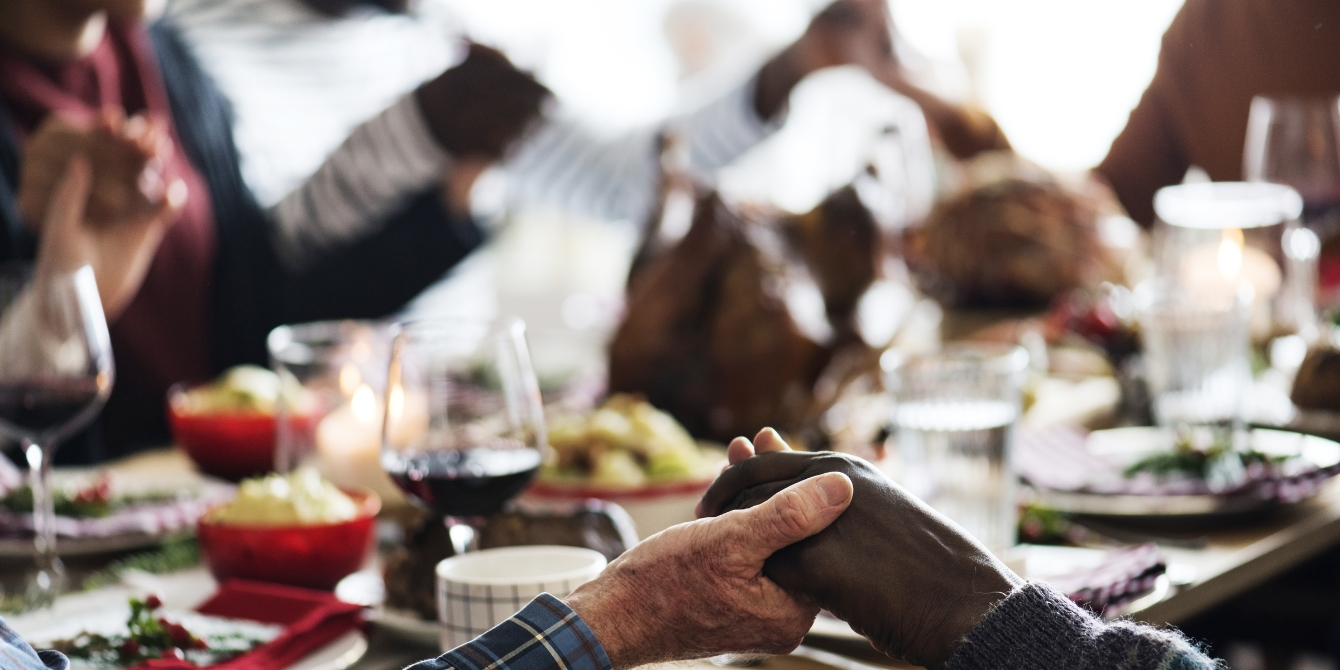 family holding hands around dinner table breaking cultural traditions