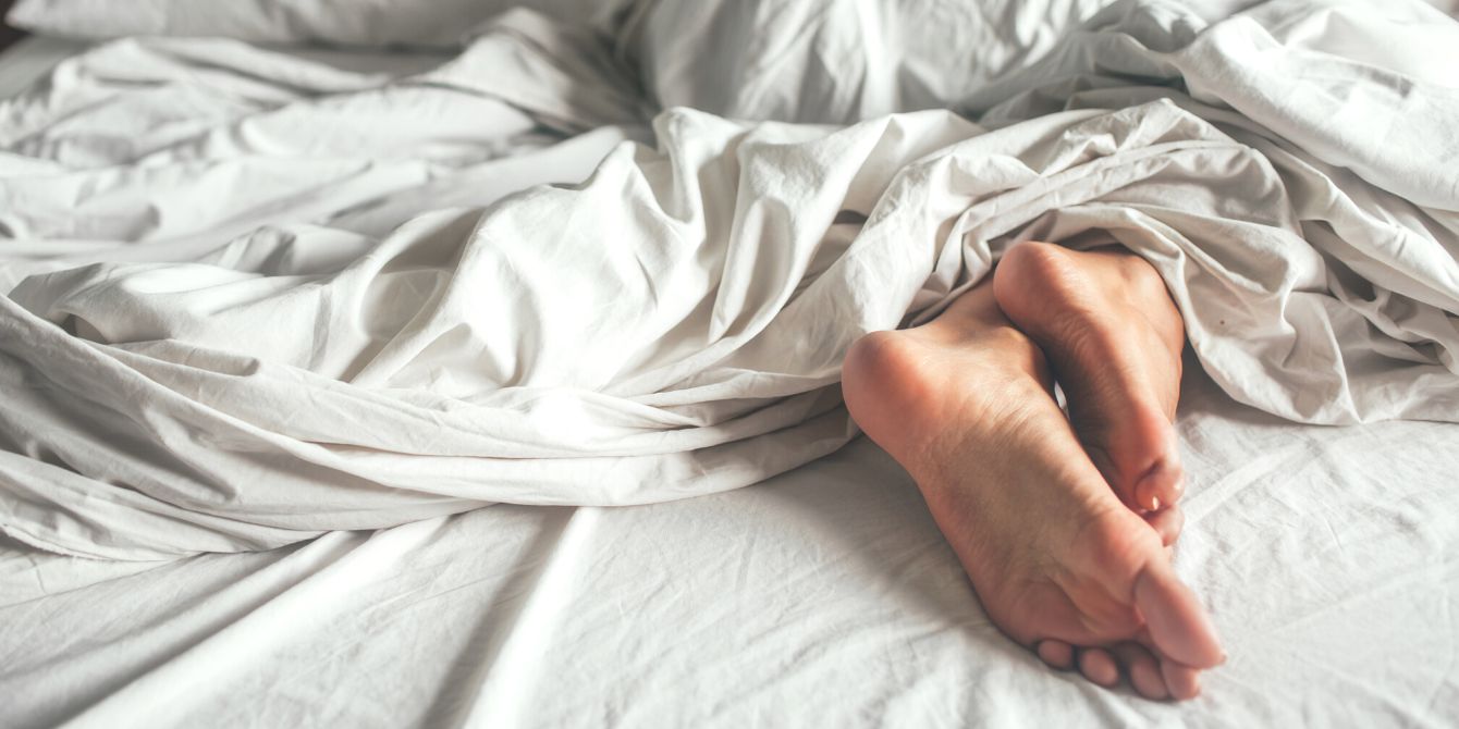 Child in pajamas sleeping in his bed without blankets, illuminated