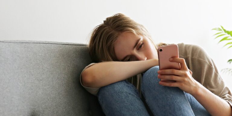 sad woman scrolling on phone female friendships after kids