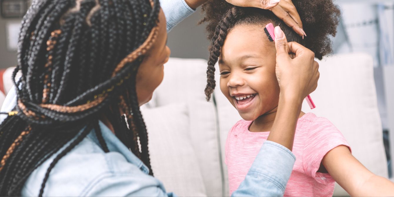 Black mother fixing her daughter's hair