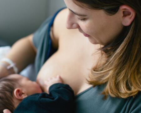 mom breastfeeding newborn baby boy Motherly