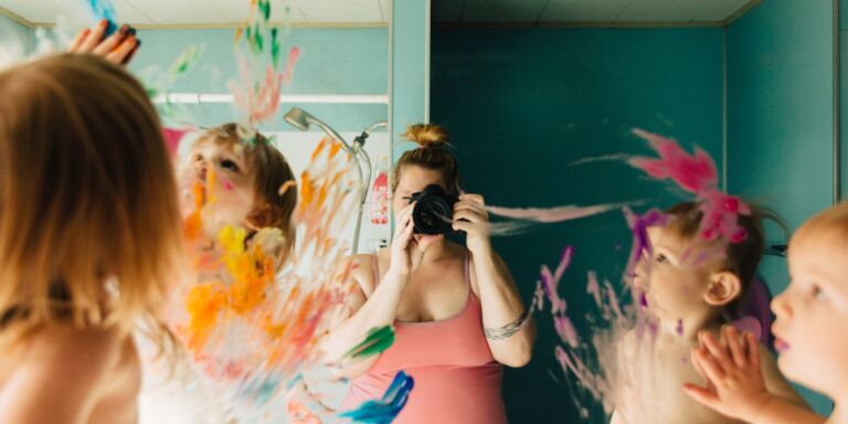 mom taking photo of kids painting on mirror mom shares messy house