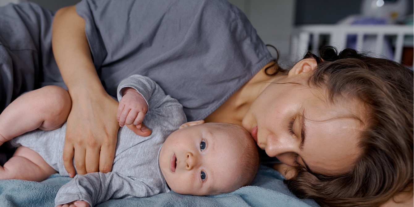 mom laying down on bed with baby