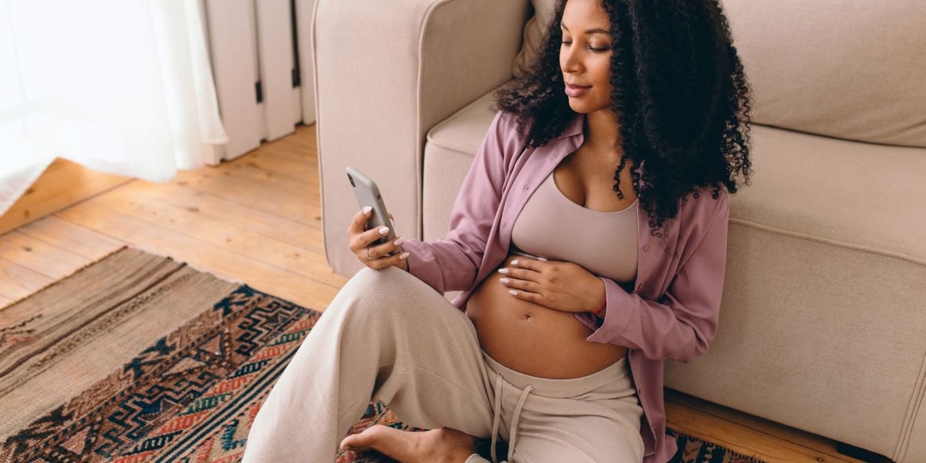 pregnant woman looking at phone - pregnancy apps and maternal mortality crisis