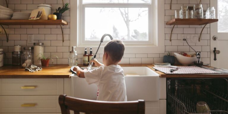 young boy doing dishes in the kitchen teaching mental load