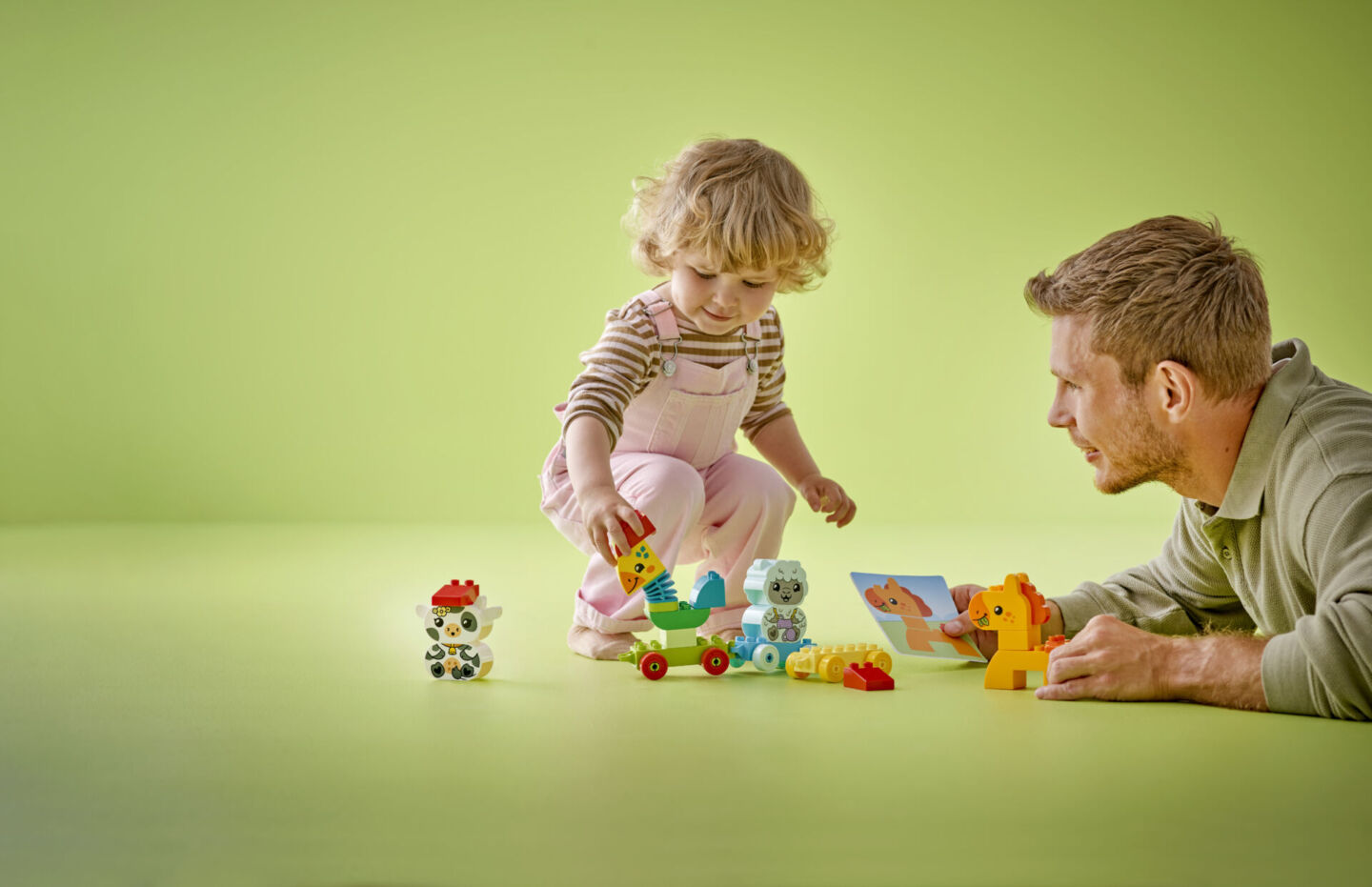 dad and toddler play with LEGO DUPLO set on green background - best toddler birthday gift