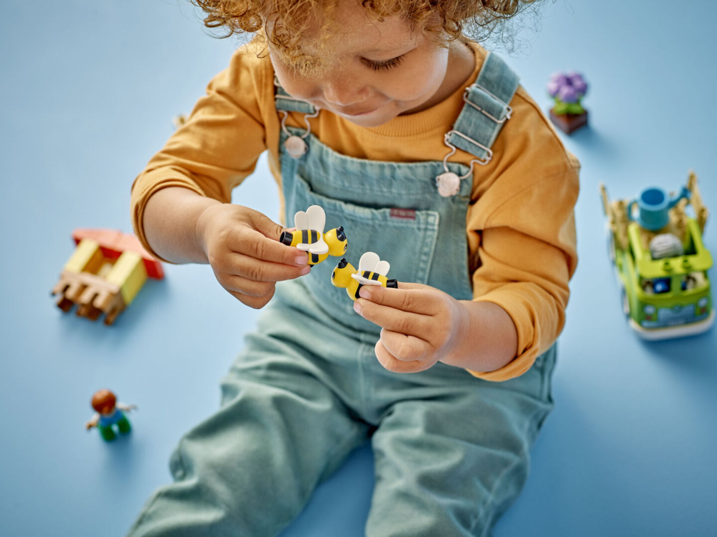 toddler playing with LEGO DUPLO figurines on blue backdrop