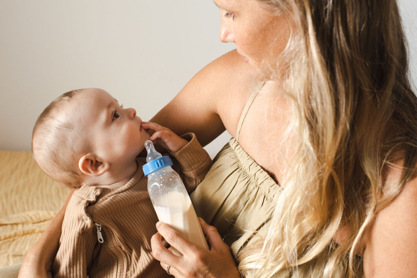 mom holding baby drinking a formula bottle - shopping for baby formula Byheart