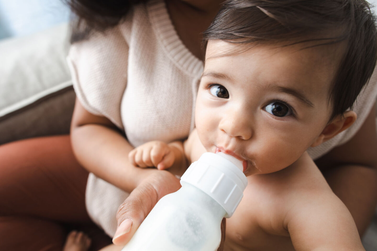 mom helping baby drink a bottle