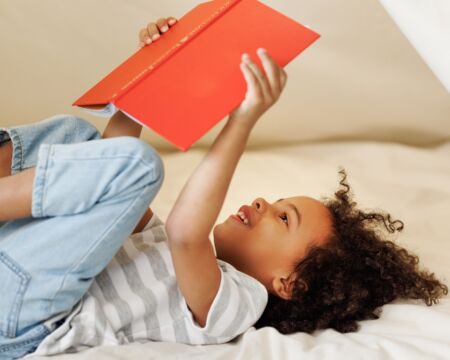 child reading a book in a fort Motherly