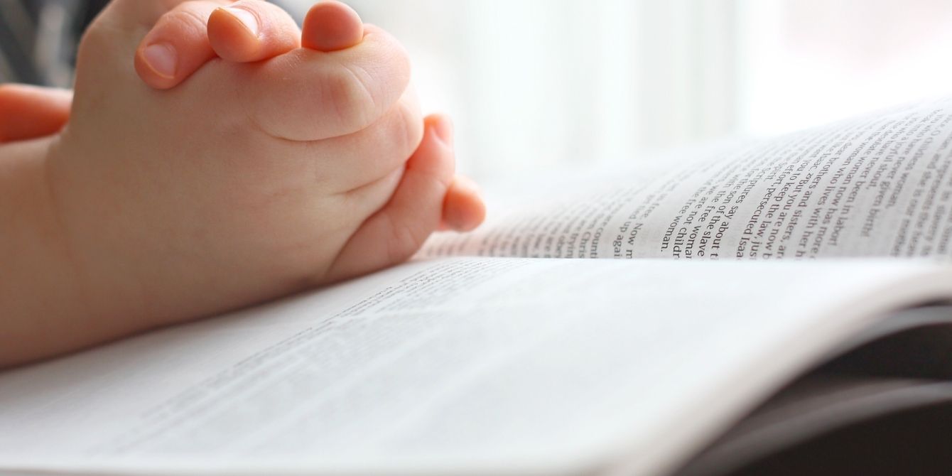 Child's clasped hands on top of Bible