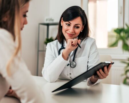 doctor talking to woman in doctors office Motherly