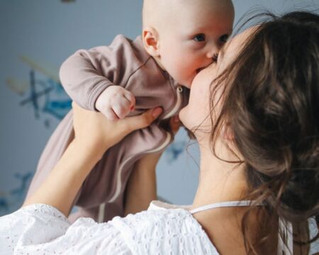 mom holding kissing baby in air Motherly