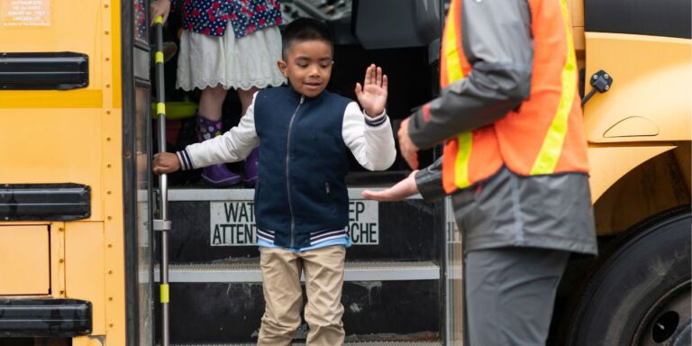 child getting off school bus - safe school bus rides - Motherly