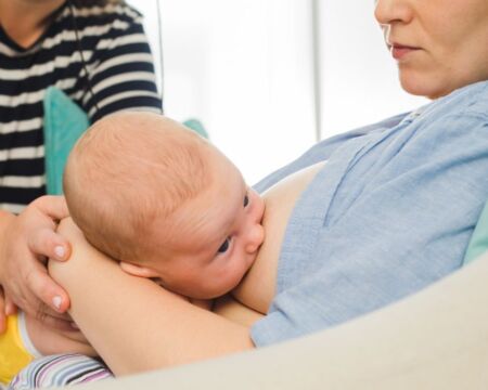 lactation consultant helping mother breastfeed Motherly