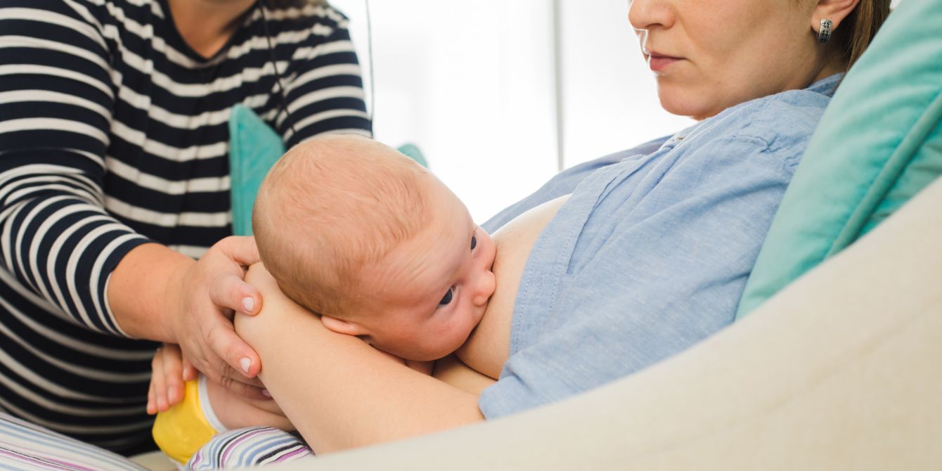 lactation consultant helping mother breastfeed - breastfeeding is a team sport