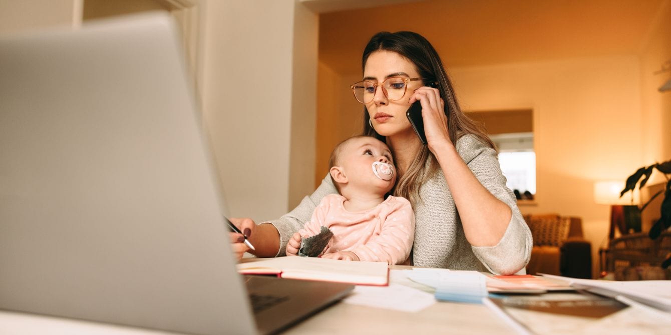 working from home with kids - mom on the phone working and holding baby