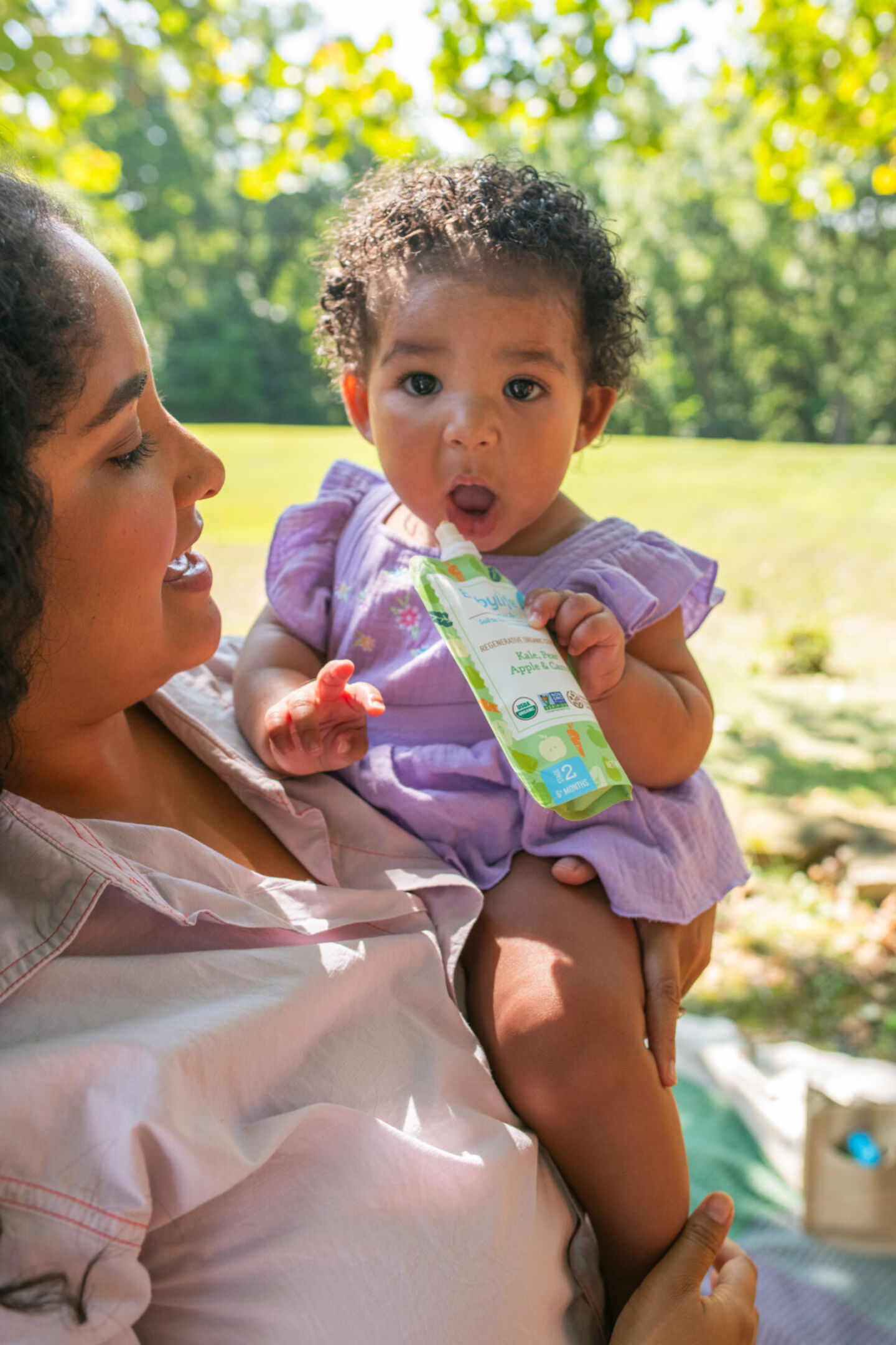 Mom holding baby eating pouch from Babylife Organics