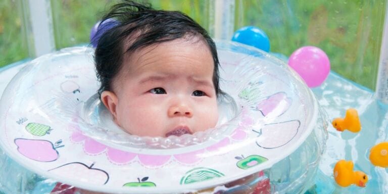 Baby wearing an infant neck float in water