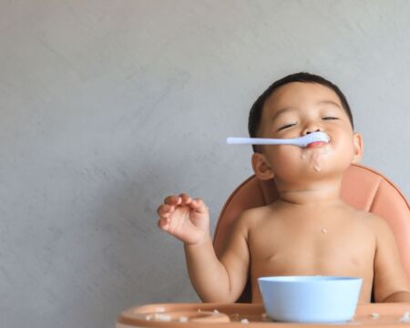 introducing solids baby eating with spoon Motherly