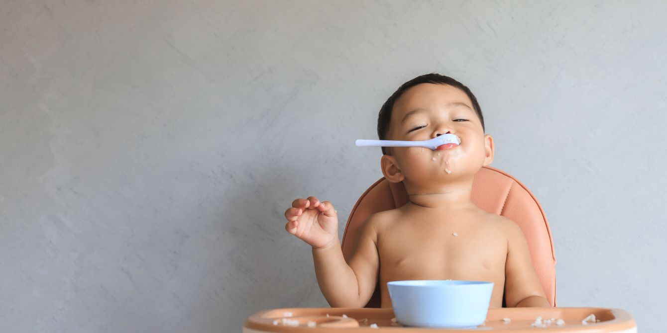 baby eating with spoon in mouth - introducing solids - motherhood essays - Motherly